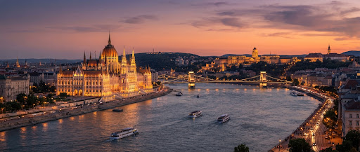 Budapest at dusk - the Danube, the Chain Bridge and the illuminated Buda Castle skyline under a warm evening sky.